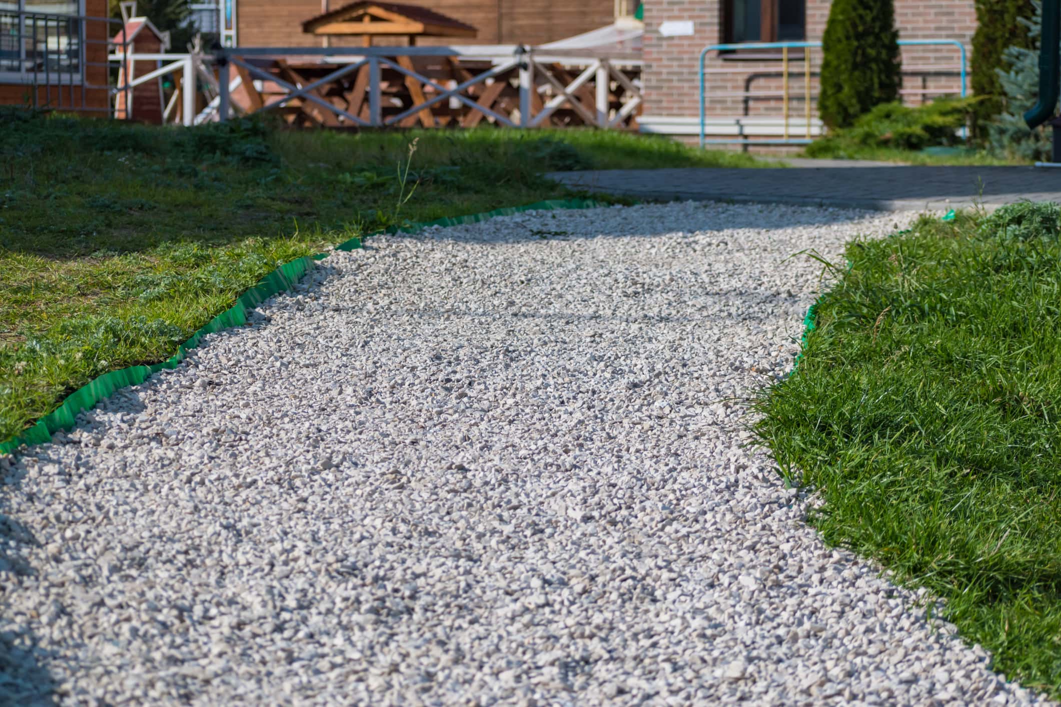 Landscape design. Path of white small stones and green grass on a sunny day